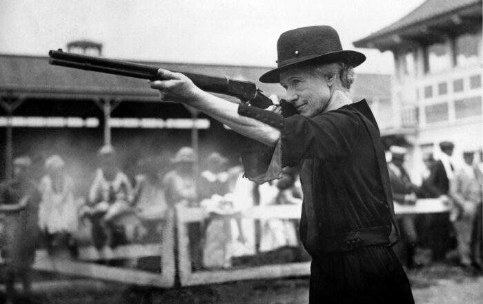 Annie Oakley takes aim with a Lever Action Rifle towards the end of her career
