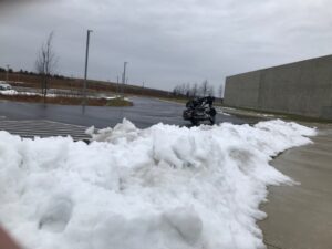 Motorcycle in a parking lot near some melting snow