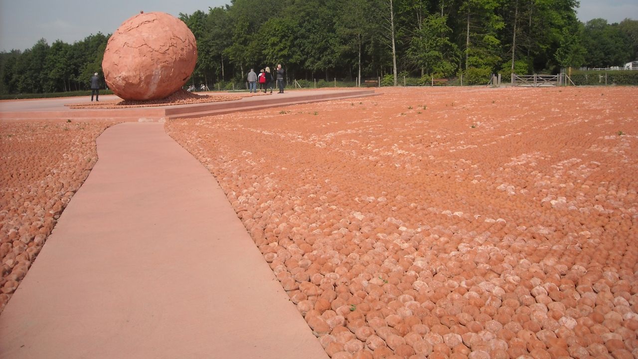 thousands of clay figures lined up near a large clay ball