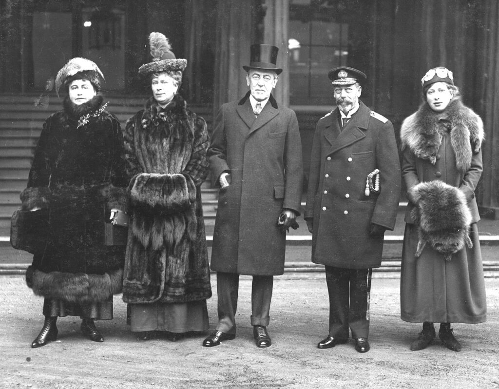 three women and two men in 1910s clothing standing on a street