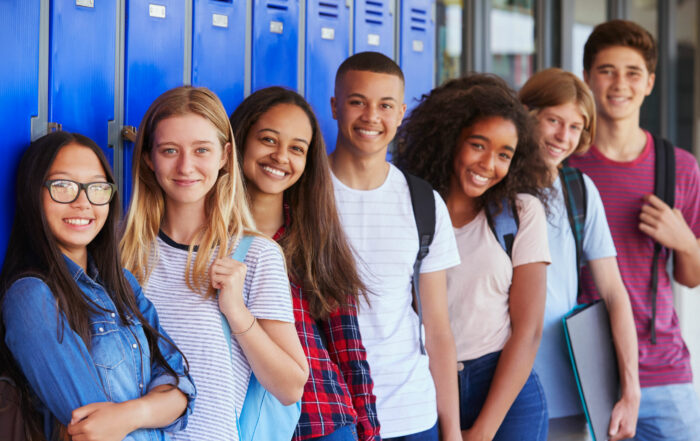 A group of seven teenage students in front of blue lockers.